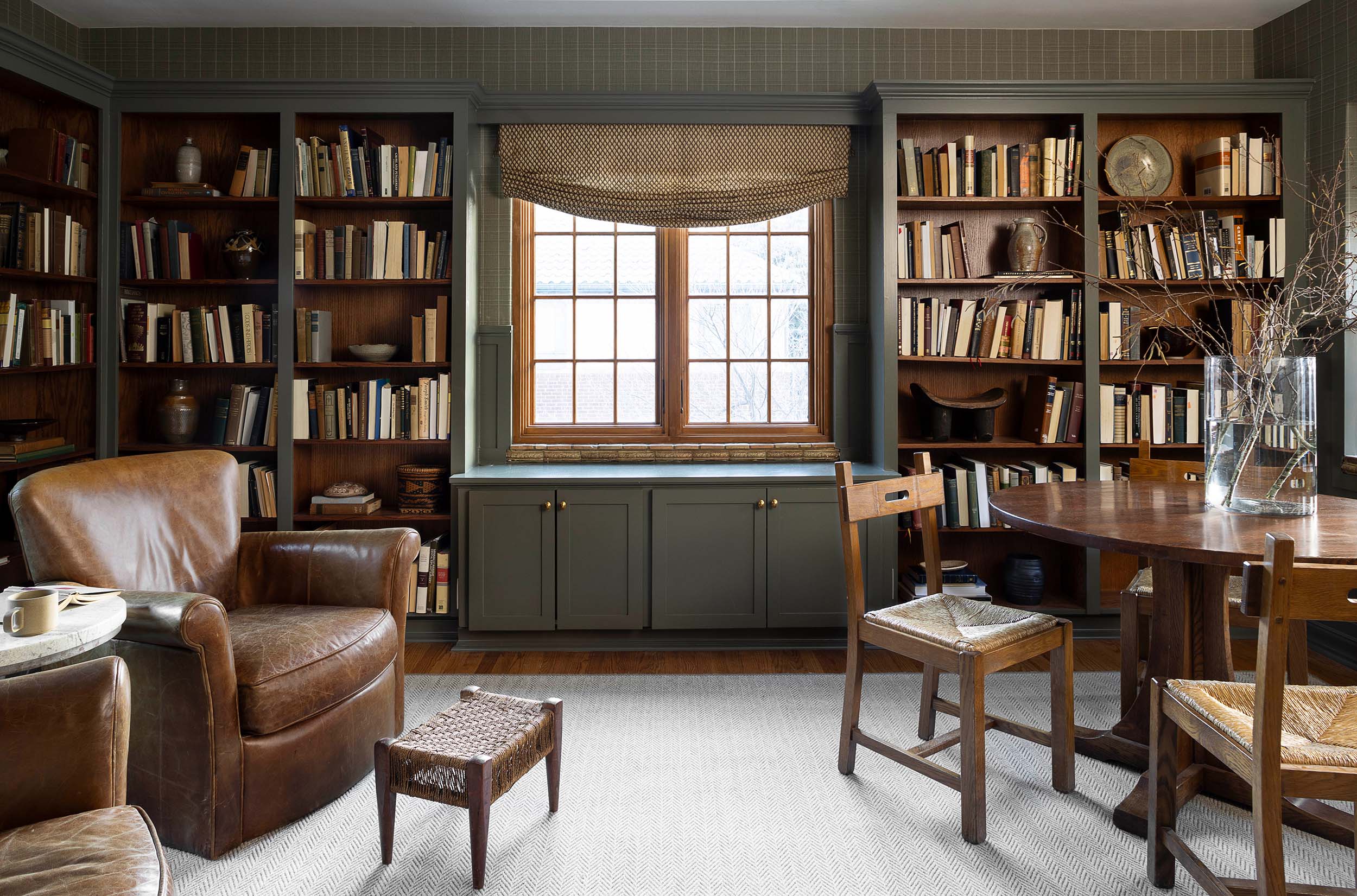 Leather armchairs with wood bookshelves in private library